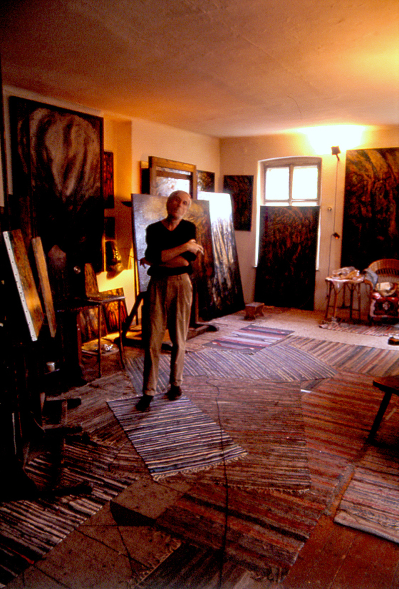 Figure standing in a studio filled with canvases
