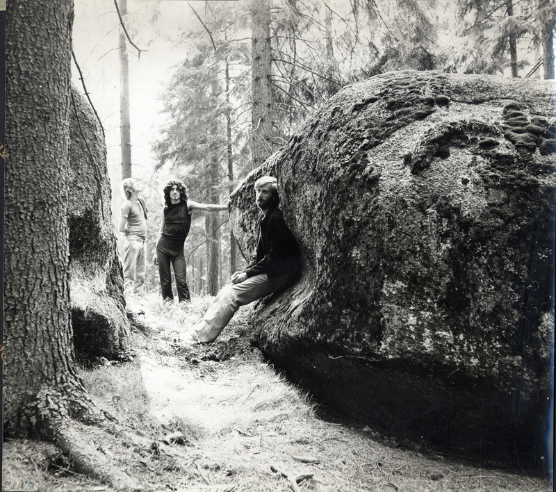 Figure beside large boulders in a forest